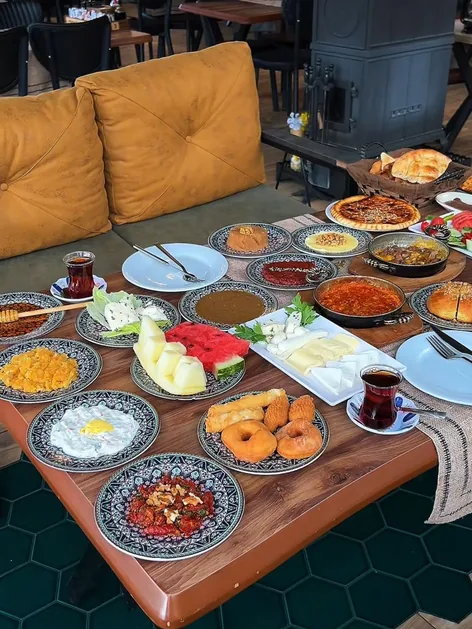 Odun sobasının yanındaki taba deri kanepede kurulu kahvaltı sofrası
