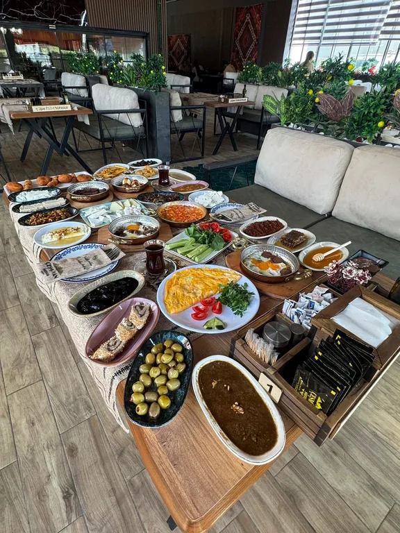 Uzun kahvaltı masasında yan yana dizilmiş otuza yakın küçük tabak